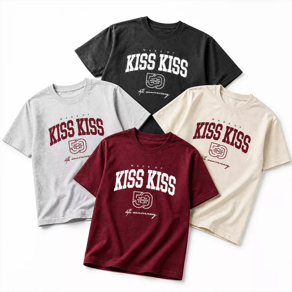 Quattro t-shirt brandizzate “KISS KISS” sono disposte in una composizione 2x2 su sfondo bianco neutro. Ogni maglietta presenta lo stesso design celebrativo con la scritta “MADE OF KISS KISS” e il logo dell’anniversario, declinato in quattro varianti colore (rosso, nero, grigio e beige). L’immagine è in stile catalogo prodotto, con illuminazione uniforme e presentazione frontale pulita.